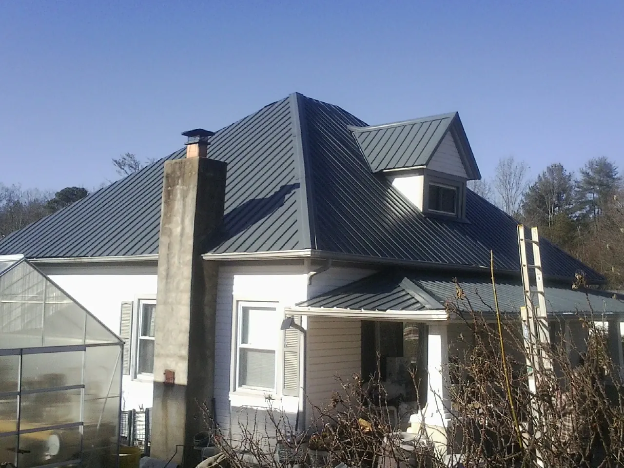 Dark blue standing seam metal roof on a white farmhouse with dormer — Slate & Tile Roof Repair by Roofing Brothers in Adamstown
