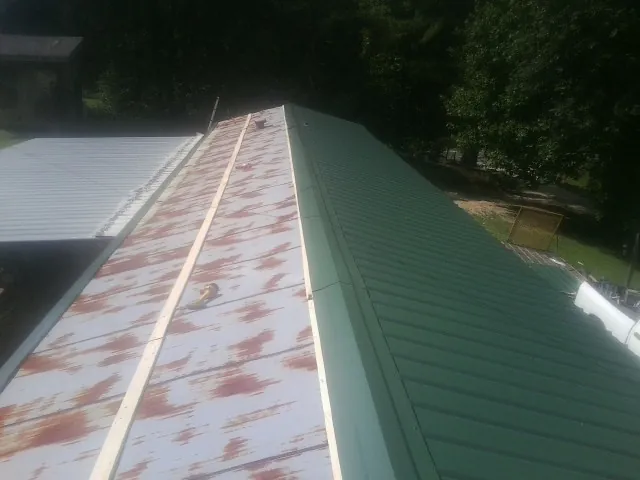 Old rusted panels beside newly installed green metal roofing — Wind Damage Roof Repair by Roofing Brothers in Adamstown