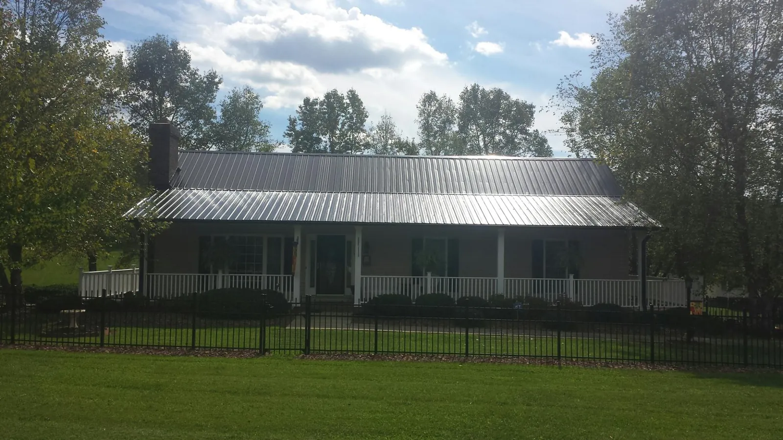Gray metal roof on a brick ranch with a full width front porch — Gutter Guard Installation work by our crew in Adamstown
