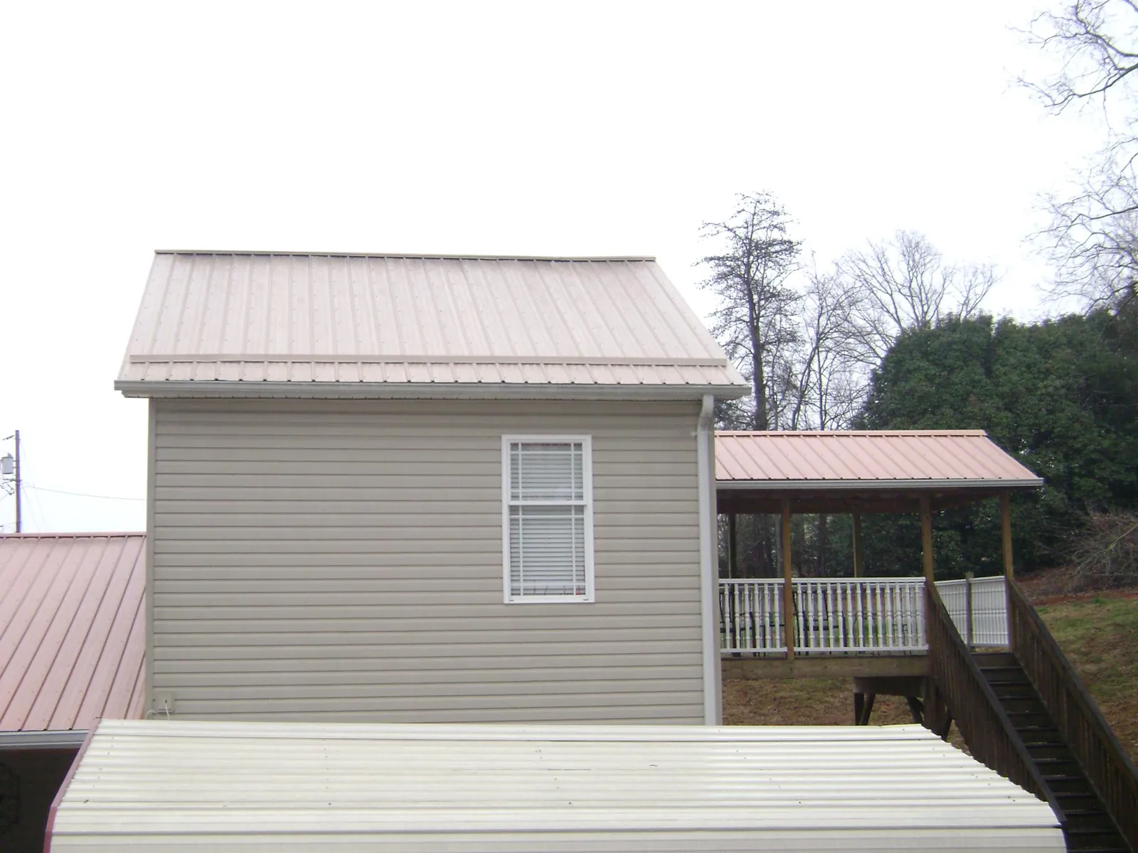 Tan metal roofs on a two story addition and attached porch, from a Roof Replacement job in Adamstown