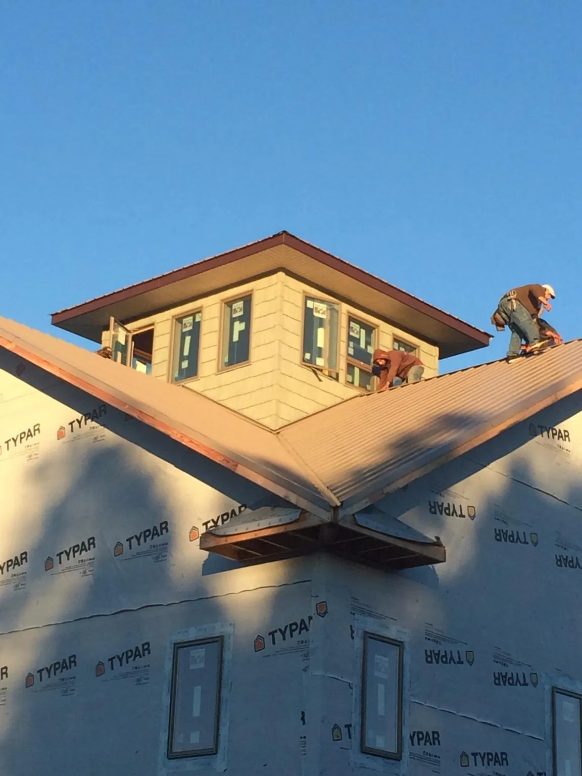 Roofers working around a rooftop cupola on a new metal roof at sunset — Roof Waterproofing in Adamstown by Roofing Brothers